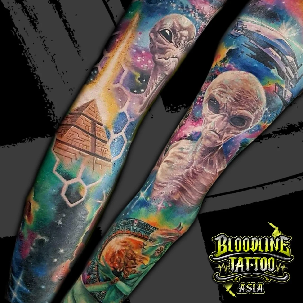 Colour sci-fi full arm sleeve tattoo with grey aliens, an Egyptian pyramid, a spaceship, and a colourful nebula at Bloodline Tattoo Bangkok.