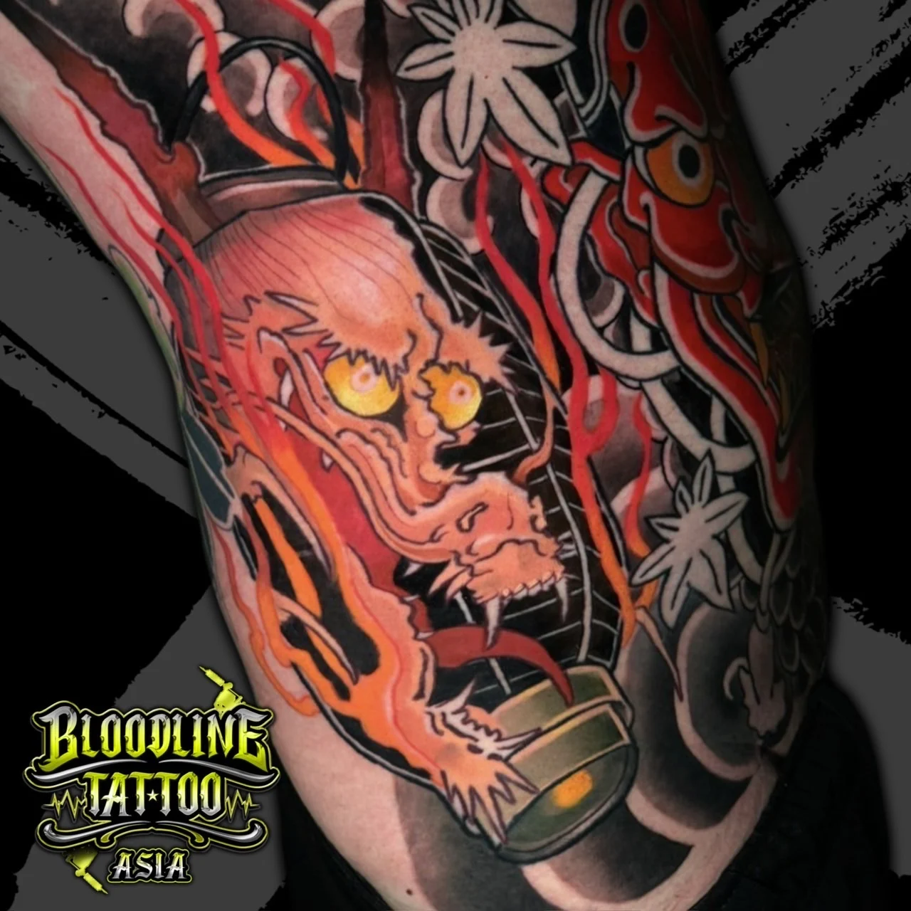Colour Japanese Irezumi tattoo of a lantern spirit and Hannya mask with orange flames on the ribs or upper arm at Bloodline Tattoo Bangkok.