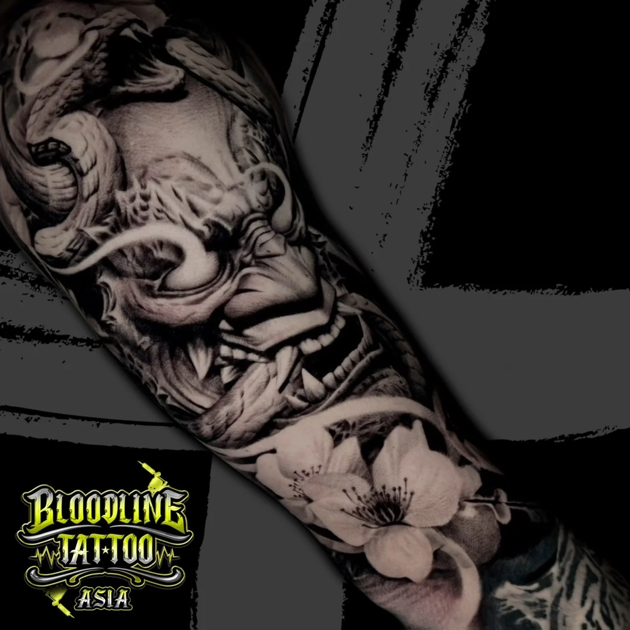Black and grey Japanese forearm tattoo of a Hannya mask coiled by a snake with cherry blossoms at Bloodline Tattoo Bangkok.
