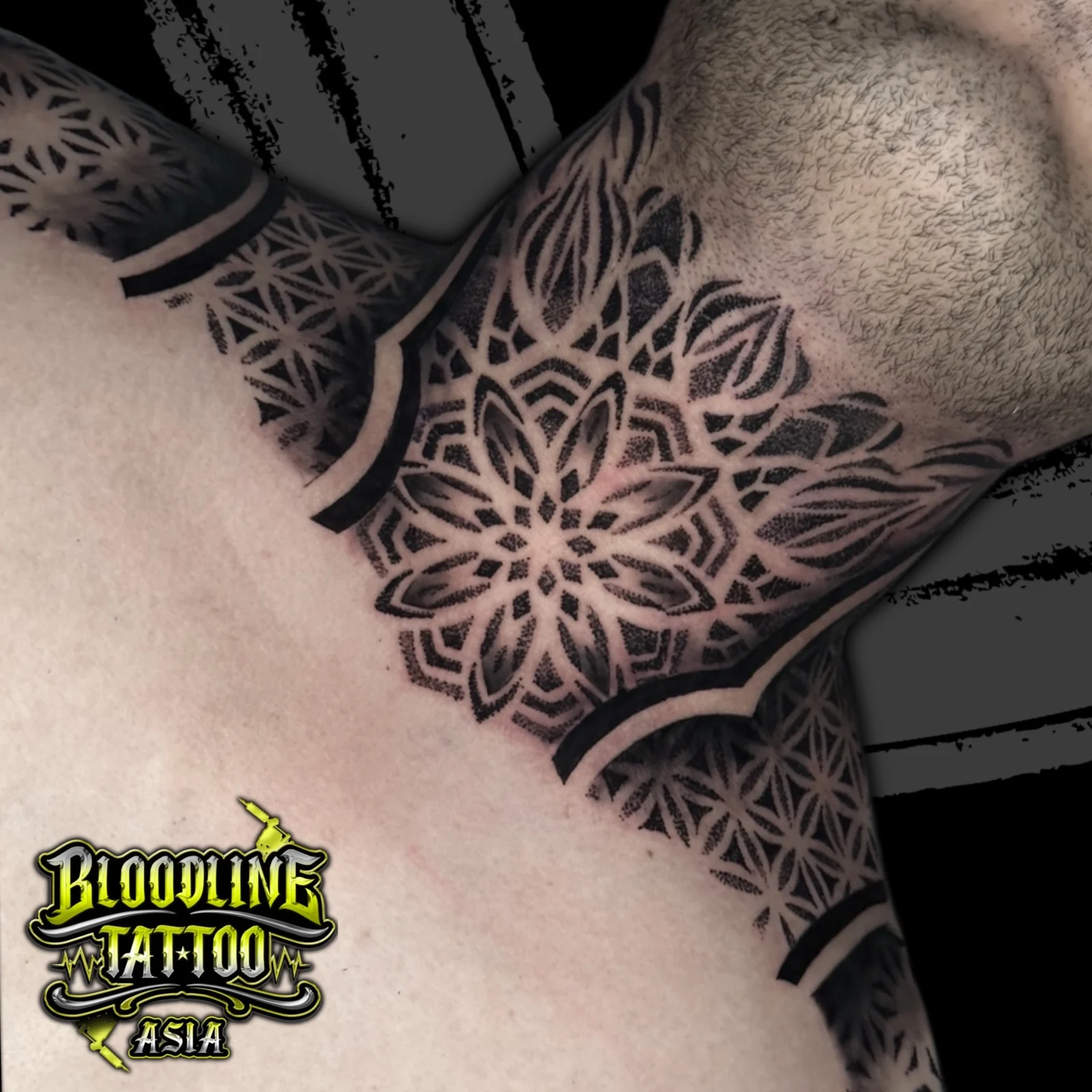 Front neck tattoo with central throat mandala flanked by Flower of Life grids across collarbones in dense dotwork, at Bloodline Tattoo Bangkok.