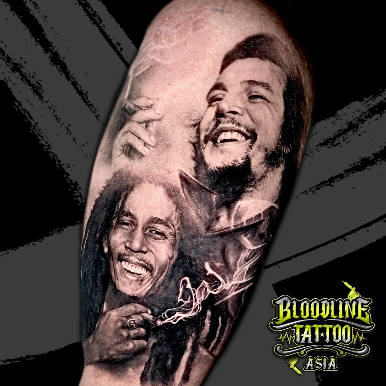 Black and grey portrait realism shoulder tattoo pairing Bob Marley smoking with dreadlocks and Che Guevara laughing with a cigar at Bloodline Tattoo Bangkok.