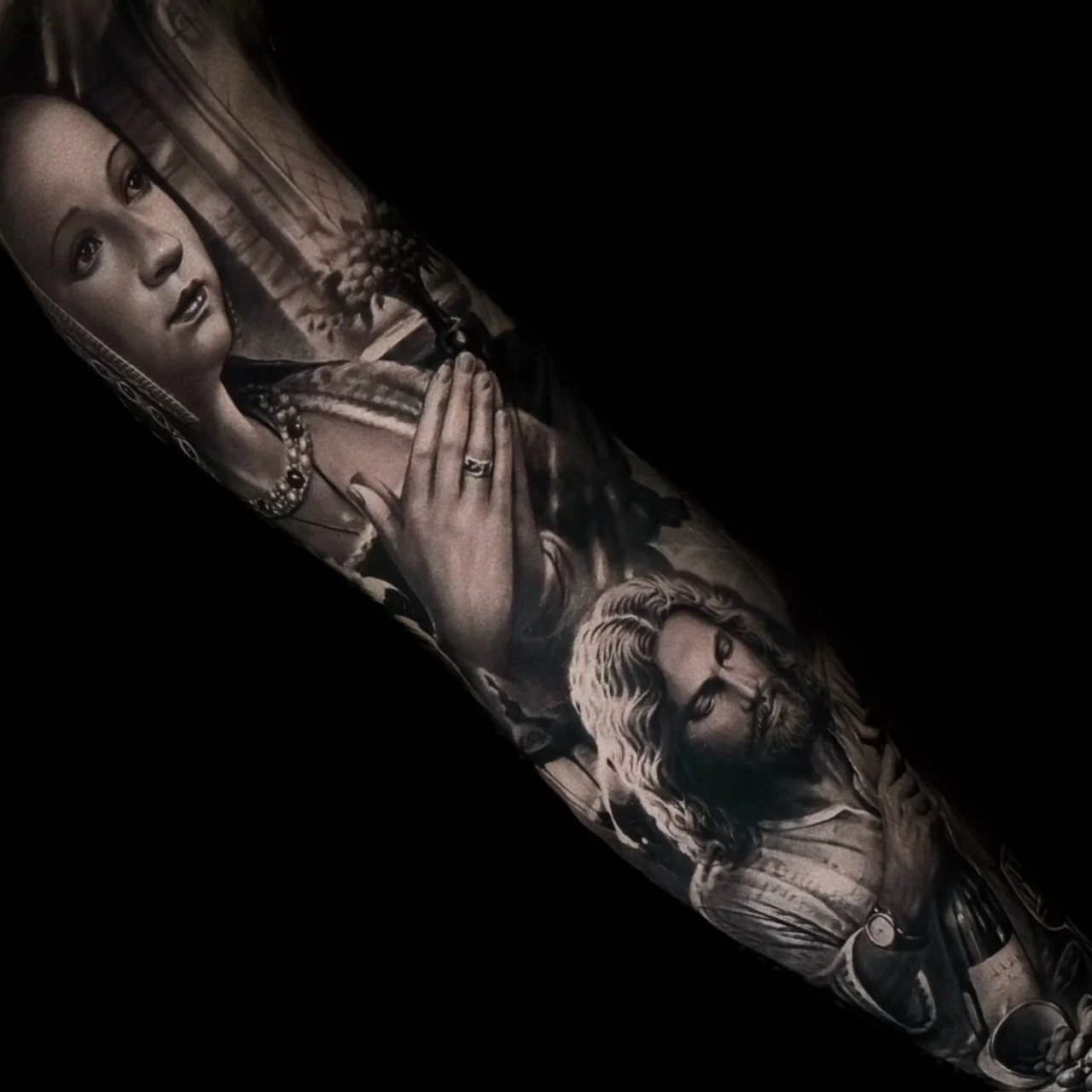 A black and grey realism sleeve with Renaissance-style portraits of a praying veiled woman above a bearded man wearing a wristwatch, at Bloodline Tattoo Bangkok.